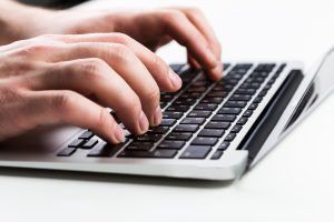 A persons hands on a keyboard typing