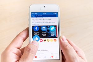 A person holding a phone with social media icons on its screen