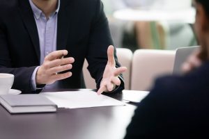 Person in a suit explaining something to someone else with his hands
