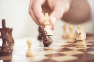 Hand moving a chess piece and knocking another one down