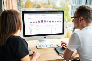 Two people looking at a computer screen looking at a metric graph