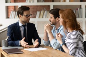 Male lawyer speaking with a couple with papers on the table