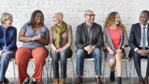 Diverse group of people sitting in a row smiling and talking